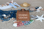 Sand, Muscheln, Geldscheine und Koffer mit Aufschrift Stornogebühr